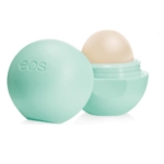 Un récipient vert clair EOS Baume à Lèvres Sphère Menthe Douce Biologique Onctueux est ouvert, montrant le baume arrondi à l'intérieur. La mention "eos" est inscrite en relief sur le couvercle, sur fond blanc. Dakar