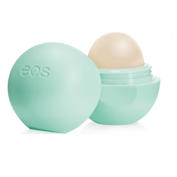 Un récipient vert clair EOS Baume à Lèvres Sphère Menthe Douce Biologique Onctueux est ouvert, montrant le baume arrondi à l'intérieur. La mention "eos" est inscrite en relief sur le couvercle, sur fond blanc. Dakar