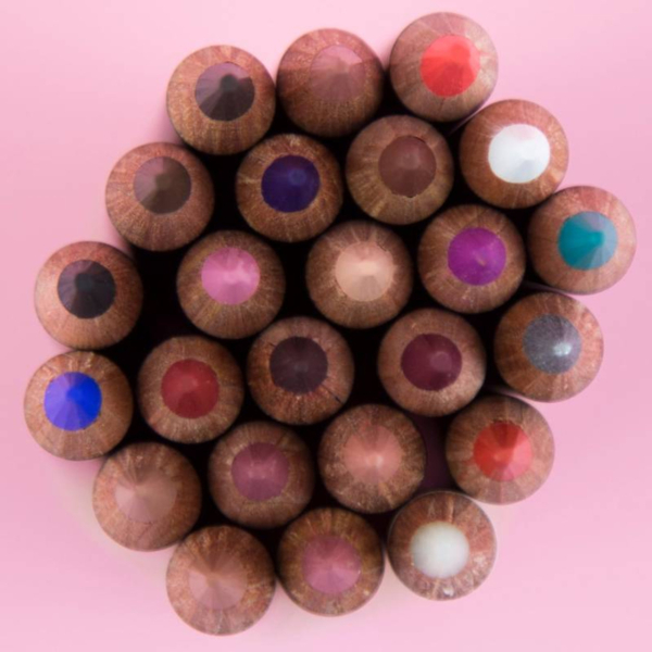 Vue rapprochée et de haut en bas des pointes de L.A. Girl Crayon Eyeliner Perfect Precision 1,49 g disposées en cercle sur un fond rose, présentant une variété de couleurs vibrantes. Dakar