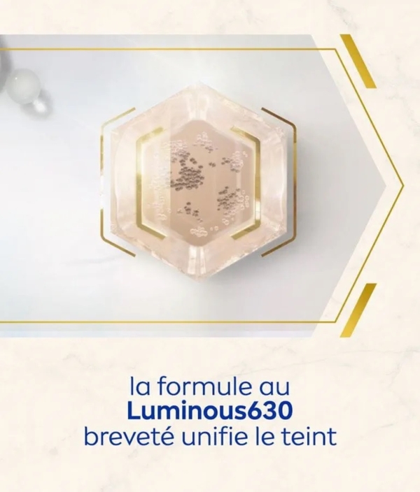 Récipient hexagonal contenant de la poudre scintillante, vue du dessus. Texte en français en dessous : "la formule au Luminous630 breveté unifie le teint". Inspiré par Nivea Crème Corps 48h Anti Vergetures Et Taches Luminous630 Teint Unifié 200 ml. Dakar