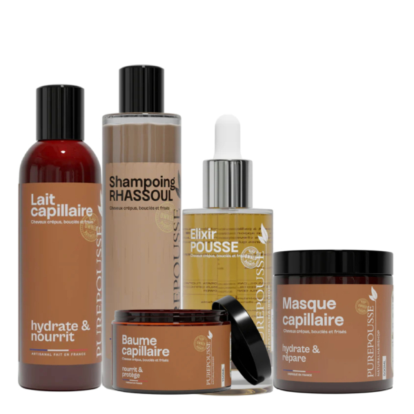 Cinq produits de soins capillaires dans des contenants bruns et beiges sont disposés ensemble. Les bouteilles et les pots sont étiquetés avec des noms tels que "Lait capillaire", "Shampoing RHASSOUL" et "Masque capillaire". Dakar