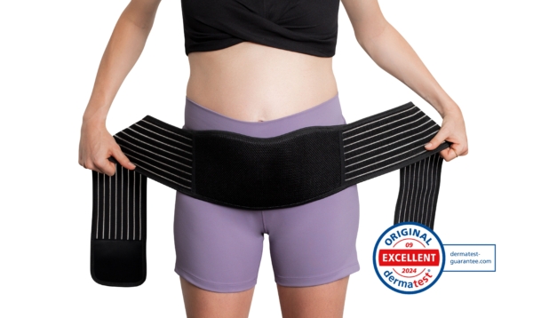 Une personne vêtue d'un crop top noir et d'un short violet ajuste le Reer Ceinture Soutient Ventre Période Grossesse autour de sa taille. Un badge de certification dermatest 2024 "Original Excellent" apparaît dans le coin inférieur droit. Dakar