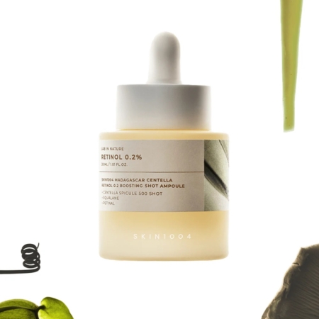 Un flacon compte-gouttes de Skin1004 Rétinol et Centella Peau Lisse et Ferme Retinol 0.2 Boosting Shot 30 ml avec un liquide brun clair est représenté sur un fond blanc avec des formes abstraites vertes et noires. Dakar