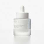 Un flacon compte-gouttes en verre givré étiqueté "Skin1004 Sérum Ampoule Raffermissant au Matrixyl Centella et Hyaluron Peau Rajeunie 30 ml", avec un bouchon et un compte-gouttes blancs, contenant un sérum de soin pour la peau, sur un fond blanc uni. Dakar