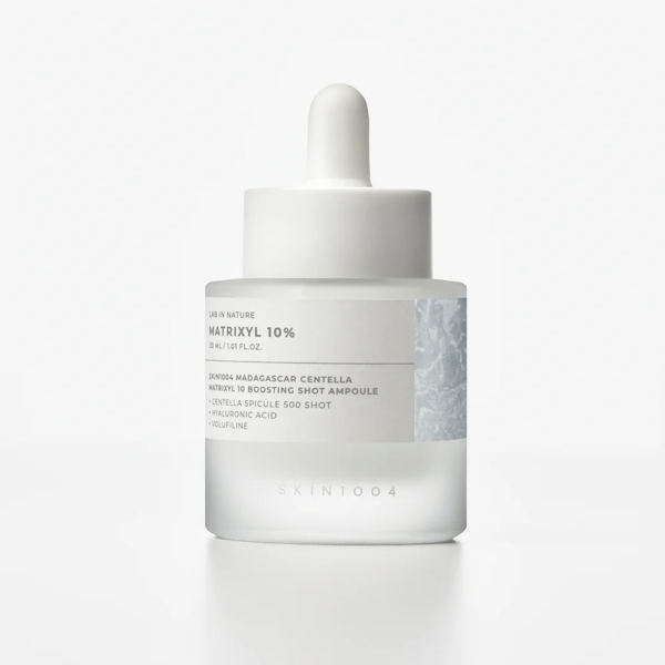 Un flacon compte-gouttes en verre givré étiqueté "Skin1004 Sérum Ampoule Raffermissant au Matrixyl Centella et Hyaluron Peau Rajeunie 30 ml", avec un bouchon et un compte-gouttes blancs, contenant un sérum de soin pour la peau, sur un fond blanc uni. Dakar