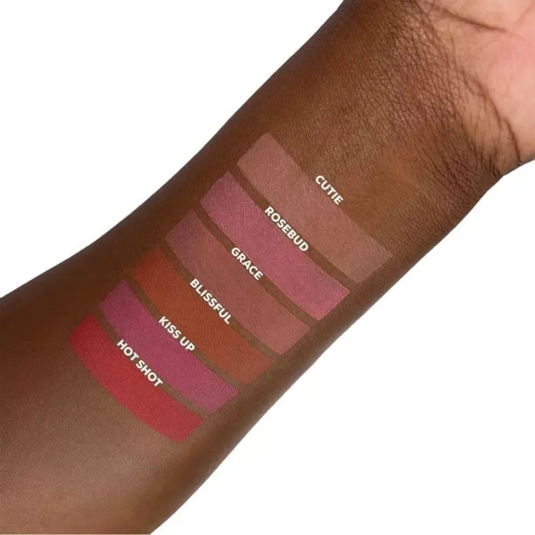 Un avant-bras présente six échantillons de L.A Girl Blush Lèvres et Joues Soft Matte Cream Blush 8 ml, étiquetés Cutie, Rosebud, Grace, Blissful, Kiss Up et Hot Shot - des teintes allant du nude au rouge profond - sur une peau foncée. Dakar