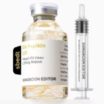 Un flacon transparent étiqueté "Sungboon Editor Ampoule Anti Age Lifting Intensif aux Peptides de Soie 35 ml", avec des fils de soie à l'intérieur, est posé à côté d'une seringue assortie sur un fond blanc. Dakar