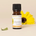 Un petit flacon brun d'Aroma Zone Antioxydant Vitamine E naturelle 5ml se trouve devant une fleur jaune sur fond beige, avec une feuille verte à proximité. Dakar