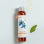 Un flacon d'Aroma Zone Huile de Nigelle BIO (Cumin noir) 100ML avec un bouchon argenté, des illustrations de fleurs bleues sur l'étiquette, deux gouttes d'huile, et une feuille verte sur un fond bleu clair. Dakar