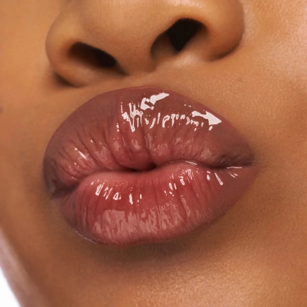 Gros plan sur des lèvres lisses et brillantes portant le Gloss à Lèvres Choco Bomb 01 Chocoholic 10 ml en rose nude brillant, avec une partie du nez visible et le fini ultra réfléchissant mis en évidence. Dakar