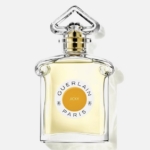Un flacon en verre transparent étiqueté "Guerlain Jicky Eau de parfum Femme 75ml", rempli d'un liquide jaune pâle et surmonté d'un bouchon décoratif, est présenté sur un fond clair. Dakar