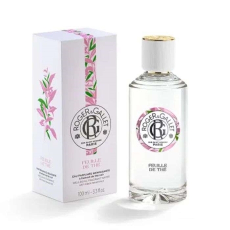 Un flacon transparent de Roger et Gallet Feuille de Thé Eau de parfum 100ML avec un bouchon blanc et une étiquette ronde en texte noir se trouve à côté de sa boîte florale blanche et rose. Dakar
