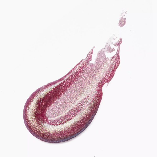 Le brillant à lèvres Catrice Diamond Glaze Brillant 3 ml en rose et or glisse sur un fond blanc, formant une forme de goutte aux reflets irisés et étincelants. Dakar