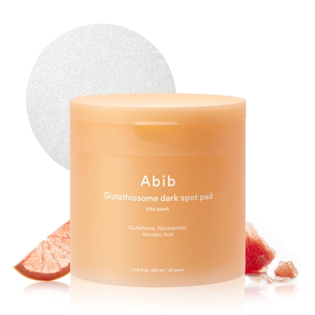 Une boîte orange de Abib Tampons Toniques Anti Taches Vitamine C Niacinamide et Glutathion 60 pads est présentée avec des tranches de pamplemousse et un tampon rond texturé en arrière-plan. L'étiquette met en évidence le Glutathion, le Niacinamide et la Vitamine C. Dakar