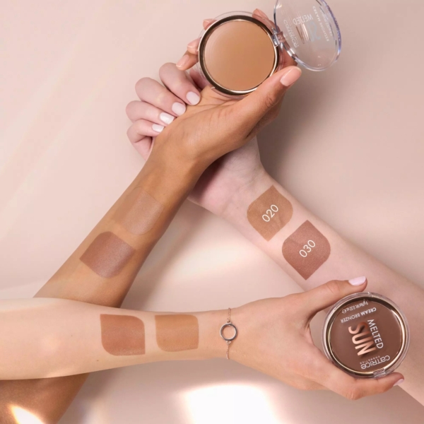 Deux bras aux teints différents présentent des échantillons de Catrice Melted Sun Crème Bronzeur Teint Hâlé Fini Mat 9 g dans les teintes 020 et 030, chacun tenant un poudrier ouvert pour montrer l'aspect de la poudre bronzante sur différentes carnations. Dakar