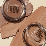 Deux contenants ouverts de Catrice Creme Bronzeur Teint Hâlé 9 g reposent sur une surface beige, avec un bronzeur crémeux étalé à côté de chacun d'eux, mettant en valeur sa texture lisse et sa riche teinte brune. Dakar