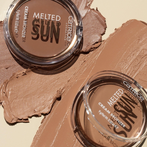 Deux contenants ouverts de Catrice Creme Bronzeur Teint Hâlé 9 g reposent sur une surface beige, avec un bronzeur crémeux étalé à côté de chacun d'eux, mettant en valeur sa texture lisse et sa riche teinte brune. Dakar