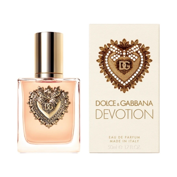 Un flacon de 50 ml de Dolce & Gabbana Devotion Eau de Parfum, orné d'un emblème en forme de cœur doré, se trouve à côté de son coffret assorti, tous deux ornés du cœur décoratif emblématique et d'un texte doré élégant. Dakar