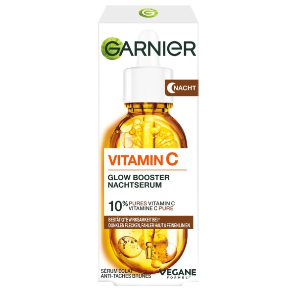 Une boîte de Garnier Skin Active Sérum Nuit Booster Éclat Vitamine C et à l'Acide Hyaluronique 30 ml, illustrée par un flacon compte-gouttes orange, met en avant 10 % de vitamine C pure, une formule végétalienne et des bénéfices pour les peaux ternes et les taches brunes. Dakar