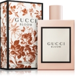 Un flacon de 30 ml de Gucci Bloom Eau de Parfum pour Femme se trouve à côté de son coffret, présentant une étiquette bordée de noir sur un fond rose pâle, tandis que le coffret présente un élégant motif floral botanique marron. Dakar