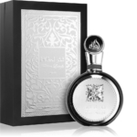 Le flacon rond et élégant de l'Eau de Parfum pour Homme Lattafa Fakhar Lattafa Men, doté d'une étiquette argentée ornée et d'un bouchon noir, est présenté devant un coffret noir et argenté gaufré assorti, orné d'écritures arabes et de motifs complexes. Dakar