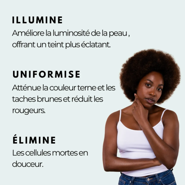 Une femme aux cheveux bouclés naturels, vêtue d'un débardeur blanc, se tient debout, une main sur le menton. Le texte français met en avant les bénéfices d'Oxyprolane Savon Exfoliant au Curcuma Éclat du Teint 220 g : éclaircissement, uniformisation du teint, exfoliation douce. Dakar