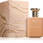 Le flacon de 100 ml de l'Eau de parfum Taskeen Caramel Cascade de PARIS CORNER, de couleur pêche, se trouve à côté de son coffret marbré assorti, tous deux ornés de touches dorées et d'un texte en arabe. Dakar