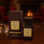 Un flacon et une boîte de Tom Ford Tobacco Vanille Eau de parfum sont posés sur une table en bois avec un cigare, tandis que des chaises longues floues et une cheminée créent un arrière-plan accueillant et confortable. Dakar