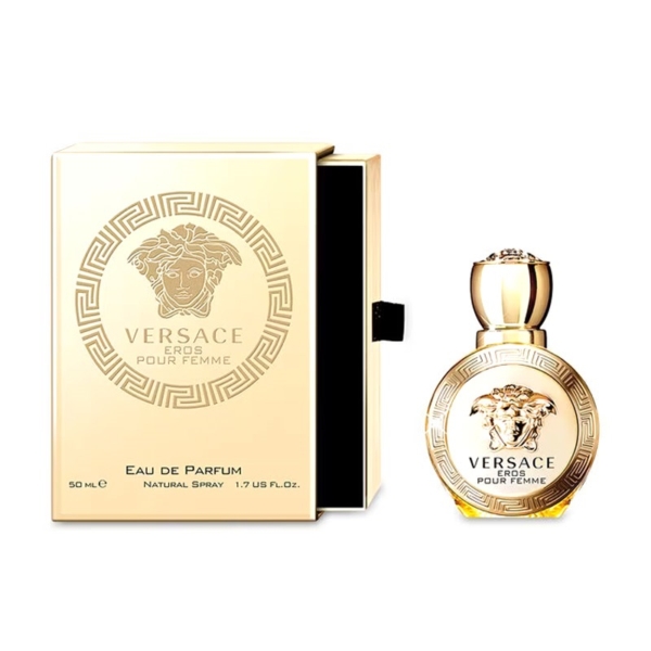 Un coffret en or et un flacon rond de Versace Eros Pour Femme 50ml, tous deux ornés du logo de la Méduse et du motif de la clé grecque. Le flacon est muni d'un bouchon en or, tandis que la boîte partiellement ouverte se trouve à côté. Dakar