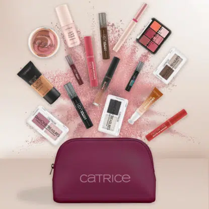 Une trousse de maquillage Catrice d'Univers Cosmetix, de couleur prune, est entourée de divers produits Catrice disposés en éventail sur un fond clair, avec de la poudre rose dispersée derrière eux. Dakar