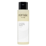 Un flacon de shampooing breveté Peptide 132 Ultra Perfect Hair Bonding Shampoo de COSRX, avec un bouchon noir et une étiquette minimaliste blanche et beige avec de subtiles lignes ondulées. Dakar