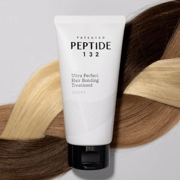 Un tube blanc étiqueté "Peptide 132 Ultra Perfect Hair Bonding Treatment" est posé sur des mèches de cheveux blonds, bruns et foncés entremêlés, soulignant le thème du soin des cheveux. Dakar