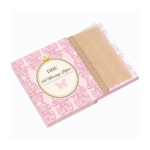 Un paquet ouvert de Dhc 100 Feuilles Absorbantes de Sébum révèle de fines feuilles roses à l'intérieur. La couverture rose présente une étiquette circulaire avec un papillon et des motifs élégants pour une touche décorative. Dakar