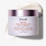 Un pot de Fresh Crème Hydratante et Réparatrice pour Visage à la Rose 50 ml avec un couvercle rose lavande est posé sur une surface blanche à côté d'une couche de crème, montrant sa formule hydratante et le format 50 ml clairement indiqué sur l'étiquette. Dakar