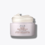 Un pot rose clair de Fresh Rose Deep Hydration Crème hydratation Rose 50ml (Copie) est posé avec son couvercle, révélant un hydratant blanc crémeux. Les détails du produit apparaissent en rouge foncé et en texte doré sur le pot. Dakar
