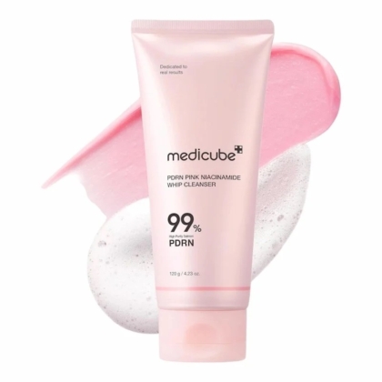 Un tube rose de Medicube PDRN Pink Niacinamide Whip Cleanser se tient debout devant des échantillons de mousse rose et blanche. L'étiquette met en évidence 99 % de PDRN et de niacinamide sur un fond blanc. Dakar