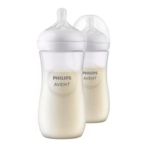 Deux biberons Philips Avent remplis de lait sont représentés avec des tétines en silicone transparent et des bouchons blancs, un biberon devant l'autre sur un fond blanc. Dakar
