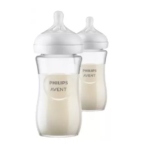 Deux biberons Philips Avent remplis de lait, avec des corps transparents et des couvercles blancs avec des tétines en silicone, sont représentés côte à côte sur un fond blanc. Dakar
