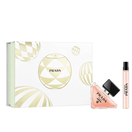 Coffret cadeau de parfum Prada comprenant une boîte décorative blanche et dorée, un flacon triangulaire de parfum rose avec un bouchon noir, et un flacon vaporisateur de voyage. Dakar