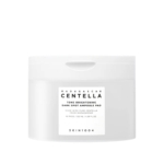 Un pot en plastique blanc étiqueté "Madagascar Centella Tone Brightening Dark Spot Ampoule Pad" par SKIN1004, contenant 60 tampons et 130 ml, avec un design simple et minimaliste. Dakar