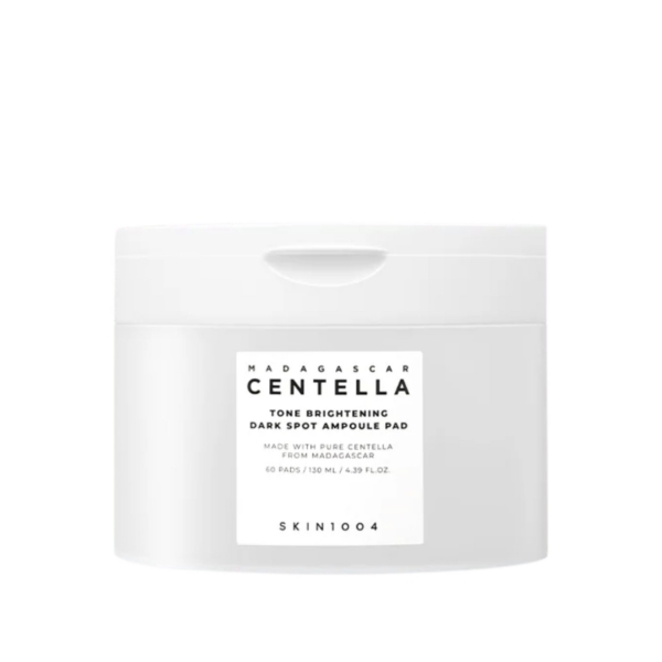 Un pot en plastique blanc étiqueté "Madagascar Centella Tone Brightening Dark Spot Ampoule Pad" par SKIN1004, contenant 60 tampons et 130 ml, avec un design simple et minimaliste. Dakar