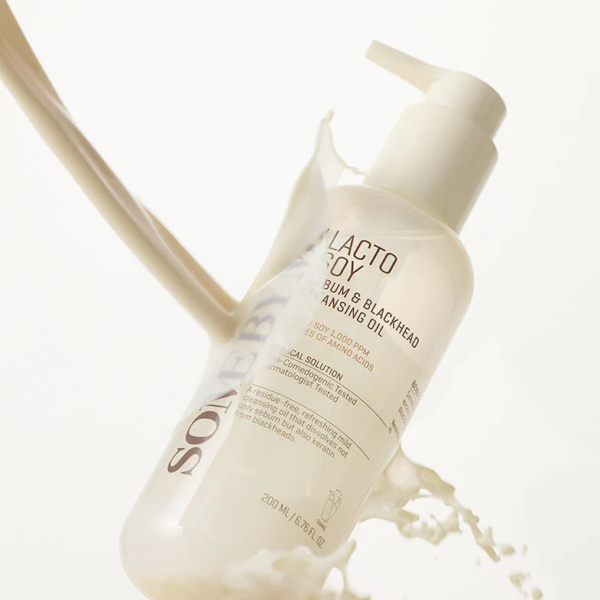 Un flacon pompe transparent de Some By Mi Huile Nettoyante Douce Équilibrante Lacto Soy Sebum & Blackhead 200 ml est éclaboussé d'un liquide crémeux sur un fond clair, affichant l'étiquette et les détails du produit. Dakar