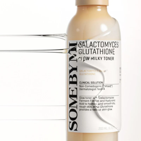 Un flacon beige de SOME BY MI Galactomyces Glutathione Glow Milky Toner avec une étiquette en noir et blanc, partiellement immergé dans de l'eau claire, créant un effet réfléchissant. Le flacon est de 200 ml. Dakar