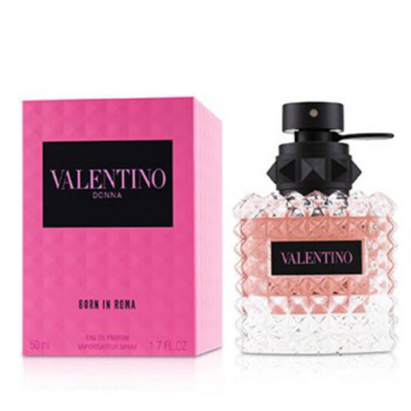 Une boîte rose et noire de Valentino Eau de Parfum Donna Born In Roma 50 ml se trouve à côté d'un flacon en verre transparent et texturé avec un liquide rose et un bouchon noir avec une étiquette rose avec le logo du produit. Dakar