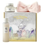 Le Beauty of Joseon Glow Charging Rice Duo est un coffret de soin composé d'un pot, d'un flacon, d'un bandeau rose et d'une boîte illustrée d'un lapin en train de moudre du riz. Dakar