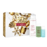Un coffret Clarins dans un écrin festif or et blanc, contenant trois produits de soin : un grand flacon de Lait Velouté et deux petits flacons de Lotion Tonique et d'Eau Micellaire Démaquillante. Dakar
