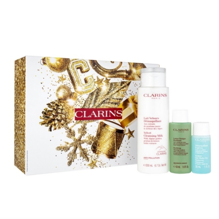 Un coffret Clarins dans un écrin festif or et blanc, contenant trois produits de soin : un grand flacon de Lait Velouté et deux petits flacons de Lotion Tonique et d'Eau Micellaire Démaquillante. Dakar