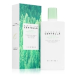 Un flacon blanc de Skin1004 Madagascar Centella Tea-Trica Soothing Sun Milk SPF50+ se trouve à côté de sa boîte, qui présente un motif de forêt verte et des détails sur le produit en vert et en texte argenté. Dakar