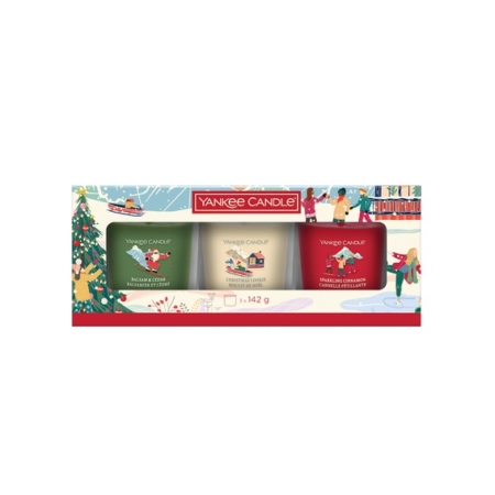 Le Coffret de Noël 2025 de YANKEL CANDLE comprend trois bougies parfumées dans les tons festifs vert, blanc et rouge, présentées dans un emballage représentant des arbres de Noël, une jeune fille avec un traîneau et des décorations hivernales. Dakar