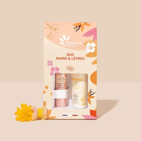 Un coffret cadeau Fleurance Nature Duo Mains & Lèvres est présenté sur un fond beige avec une fleur jaune à côté. Le coffret comprend une crème pour les mains et un baume à lèvres dans une boîte décorative aux motifs floraux. Dakar
